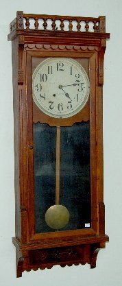 New Haven Walnut Wall Clock, "Gambia": New Haven Walnut Wall Clock, "Gambia": 8 day TO, spring wound; in a walnut case; with the pendulum and key. Not tested. 47" Long (The top crest is missing.) **Please note, this item ships F.O.B. which