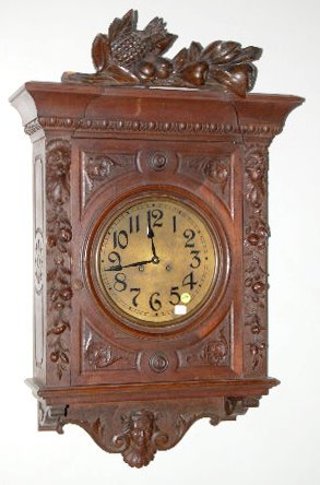 Ornate Carved Gallery Clock: Ornate Carved Gallery Clock: T & S; has a brass plate face with Arabic numerals; the case top is large carved fruit; the front sides have lion heads and carved fruit; the side has a floral design; the