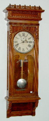 Gilbert No. 10 Walnut Wall Regulator Clock: Gilbert No. 10 Walnut Wall Regulator Clock: 8 day movement with dead beat escapement; 10" dial with seconds hand; in a carved walnut case with glass sides; with nickel weight, pendulum bob and wood pe