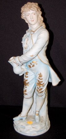 Bisque Figure of a Gentleman: Bisque Figure of a Gentleman: He is a long haired gentleman with incised eyes dressed in blue and gold floral pantaloons; he is holding a water jug by his side. It is marked "RW" and numbered 463. 17 
