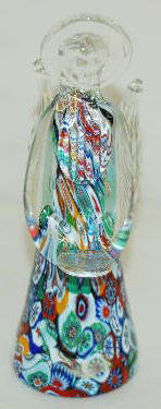 Paperweight, Millifiori, Cut Cane Angel: Paperweight, Millifiori, Cut Cane Angel: Has the colors red, blue, green, orange and white in her robe; the arms, head, wings and halo are clear; she holds a flat clear disk in front. 5 3/8" Tall No c