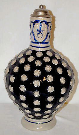 German Stoneware Pitcher, Relief Molded: German Stoneware Pitcher, Relief Molded: Marked Original Gerzit, Gerz #4; decorated with rosettes and cobalt paint; with large head on the neck of the pitcher; has a pewter lid. (There is a small dent