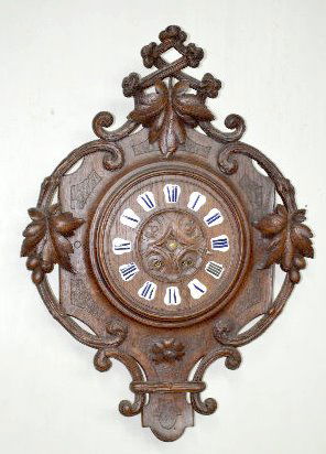 European Black Forest Style Carved Wall Clock: European Black Forest Style Carved Wall Clock: With a T&S movement in a carved oak hanging case with a wood dial and porcelain cartouche numerals. The case also has carved leaf and berry motif. The pe