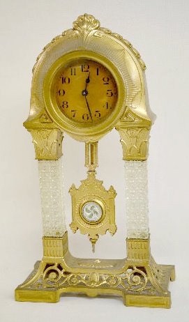 German Crystal Column Empire Clock: German Crystal Column Empire Clock: Set keywind with a celluloid dial marked Western Germany. With a metal base and top with square button columns and a Sandwich Glass pendulum. (The clock is not runn