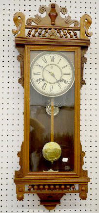 Waterbury "Bruce" Walnut Wall Clock: Waterbury "Bruce" Walnut Wall Clock: With a T&S movement; a paper dial marked "WCC"; paper labels on the back; and the pendulum and key. Not tested. 38" Long; 31" Long without the crest. Sells as is,
