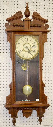 Waterbury "Eton" Oak Hanging Wall Clock: Waterbury "Eton" Oak Hanging Wall Clock: With a T&S movement; a paper dial marked "WCC"; a "Waterbury" tag inside the case; the pendulum and key. Not tested. 41" Long; 32 1/2" Long without the crest.