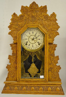 Gilbert "Concord" Oak Calendar Kitchen Clock: Gilbert "Concord" Oak Calendar Kitchen Clock: With a T&S movement; a paper calendar dial marked "G"; decorated glass door; the pendulum and key. The clock is running and striking at this time. (The bo