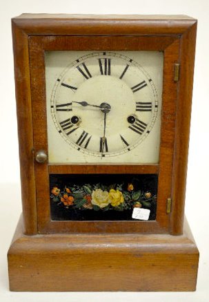 Seth Thomas Walnut Cottage Clock: Seth Thomas Walnut Cottage Clock: With a T&S movement; an unmarked painted metal dial; the pendulum and key. The walnut case has an interior label and a rose decorated door. The clock is running and s
