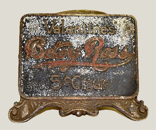 Counter Top Cigar Cutter, "Betsy Ross": Counter Top Cigar Cutter, "Betsy Ross": All metal; the front reads "Valentines Betsy Ross 5? Cigar". Appears to be complete. (There is wear and pitting to the finish.) 5 3/4" Tall x 7" Wide Sells as i