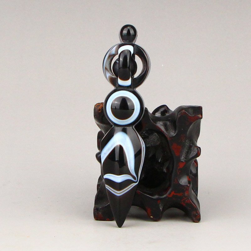 Tibetan Buddhism DZI Agate Pestle XiangMo Pendant: Tibetan Buddhism DZI Agate Pestle XiangMo Pendant Dimension: 73 x 16 x 10(mm)2.87 x 0.63 x 0.39(inches) Weight: 0.03 lbs/15.98 g The wooden stand no included.