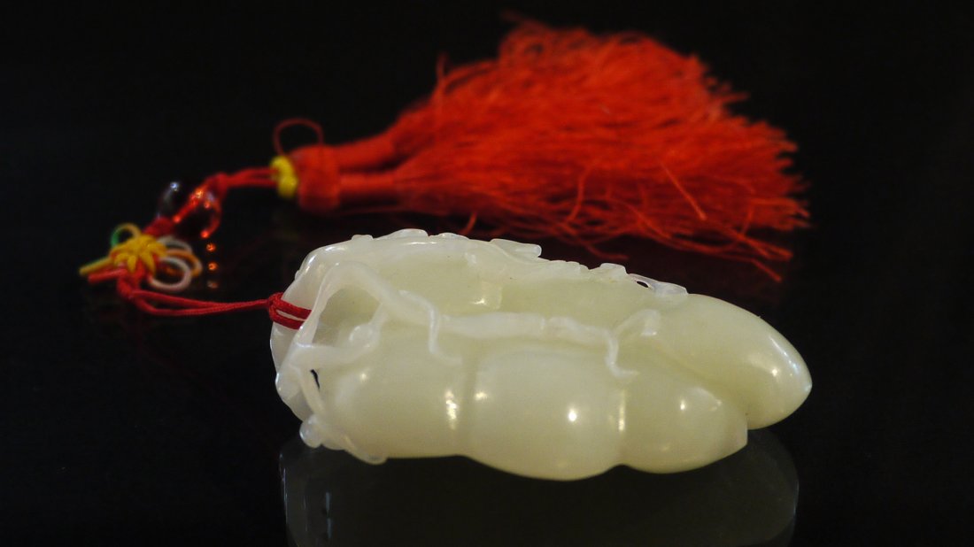 A TOP GRADE WHITE HETIAN JADE PENDANT: even coloured top grade jade, depicting two conjoining fruits with intertwined vines, weight=84g.和田一级白玉《状元封侯》把