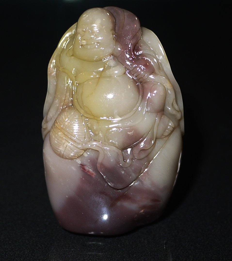 A SHOUSHAN YUEWEI LV STONE 'BUDAI BUDDHA' SEAL: pebble form seal surmounted with peaceful-minded Budai carry a bag, the stone of white and mottled brown, height 3cm, weight 128g. (recommended by our expert).寿山月尾绿&