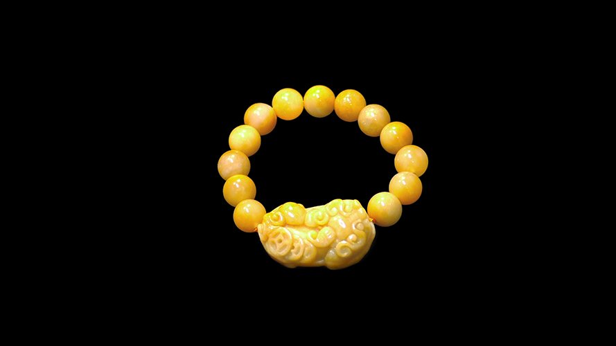 A GEBI YELLOW JADE 'PIXIU' BEADS BRACELET: comprised of thirteen round beads and carved pendant depicting crouching pixiu and cash coin, weight 65g.戈壁黄玉貔貅带珠手链