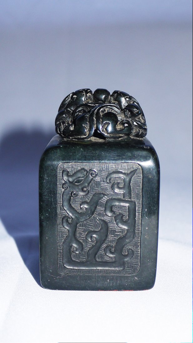 A QING AIYE GREEN SQUARE SEAL: cube form and carved with square panelof totem dragon and poetry, signed by poet, atop with two beasts sharing a pearl, six characters carved on seal face, height 9cm, width 6cm, weight 587g. (recomme