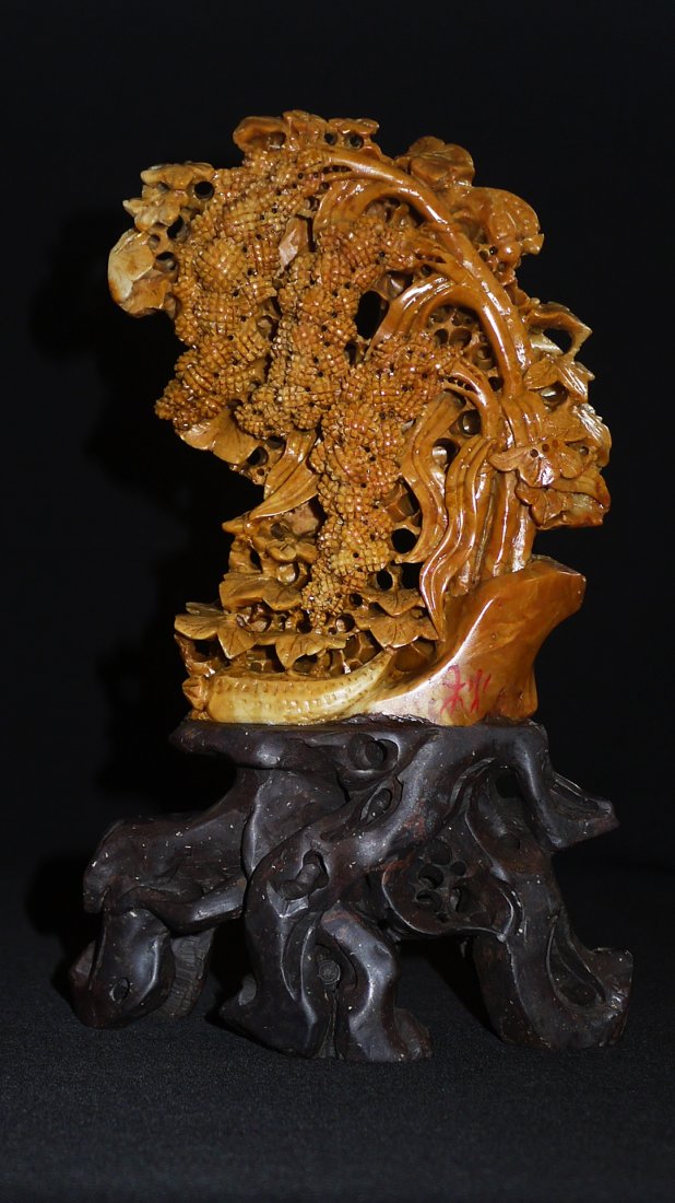 A FINE QIANTIAN SHOUSHAN STONE PENDANT: having pierced carving throughout the warm tone stone, the fruits and foliages naturalistically carved, raised atop a fitted dark wood base, height 9cm, width 4.5cm, weight 1107g.青田ĳ