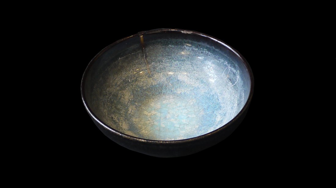 A JUN KILN BOWL: the conical bowl raised on a low foot and covered with a pale blue glaze with light mottling and crackling and decorative purple hues, the glaze running down the exterior and characterically stopping 