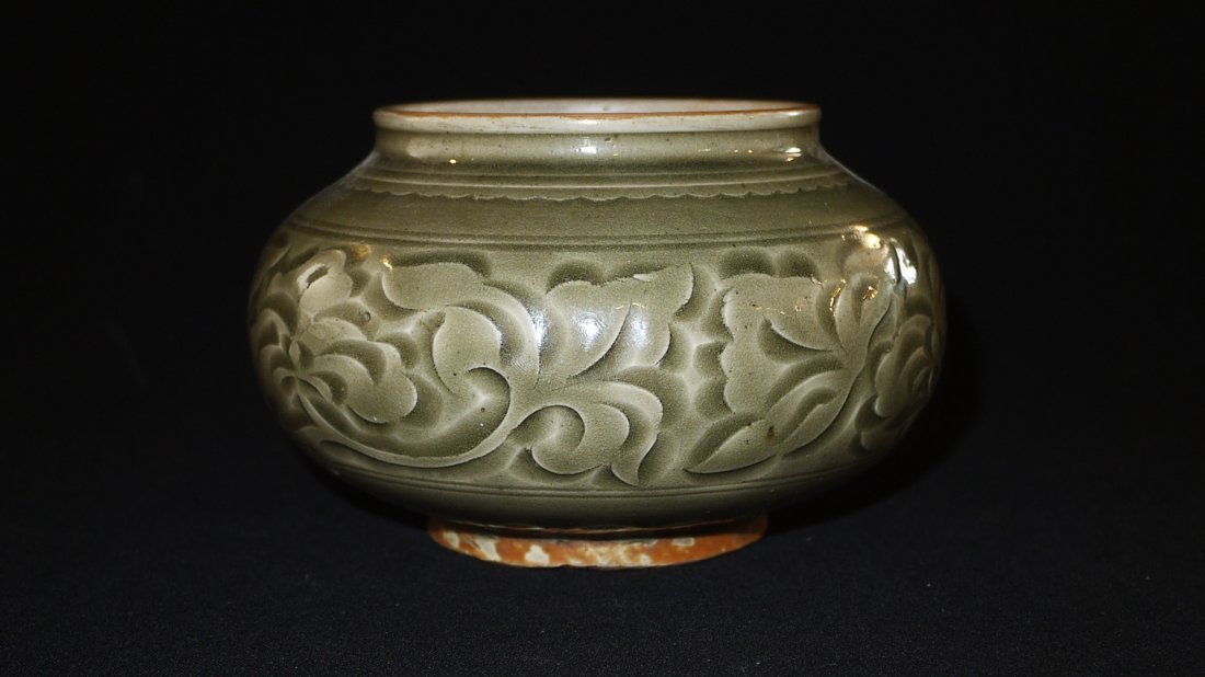 A YAOZHOU KILN 'LOTUS' JAR: of short squat form and raised on shallow foot, a subtle frieze of flora and vines on the bulged waist, upper diameter 10cm, height 9.5cm.耀州窑刻花文贯