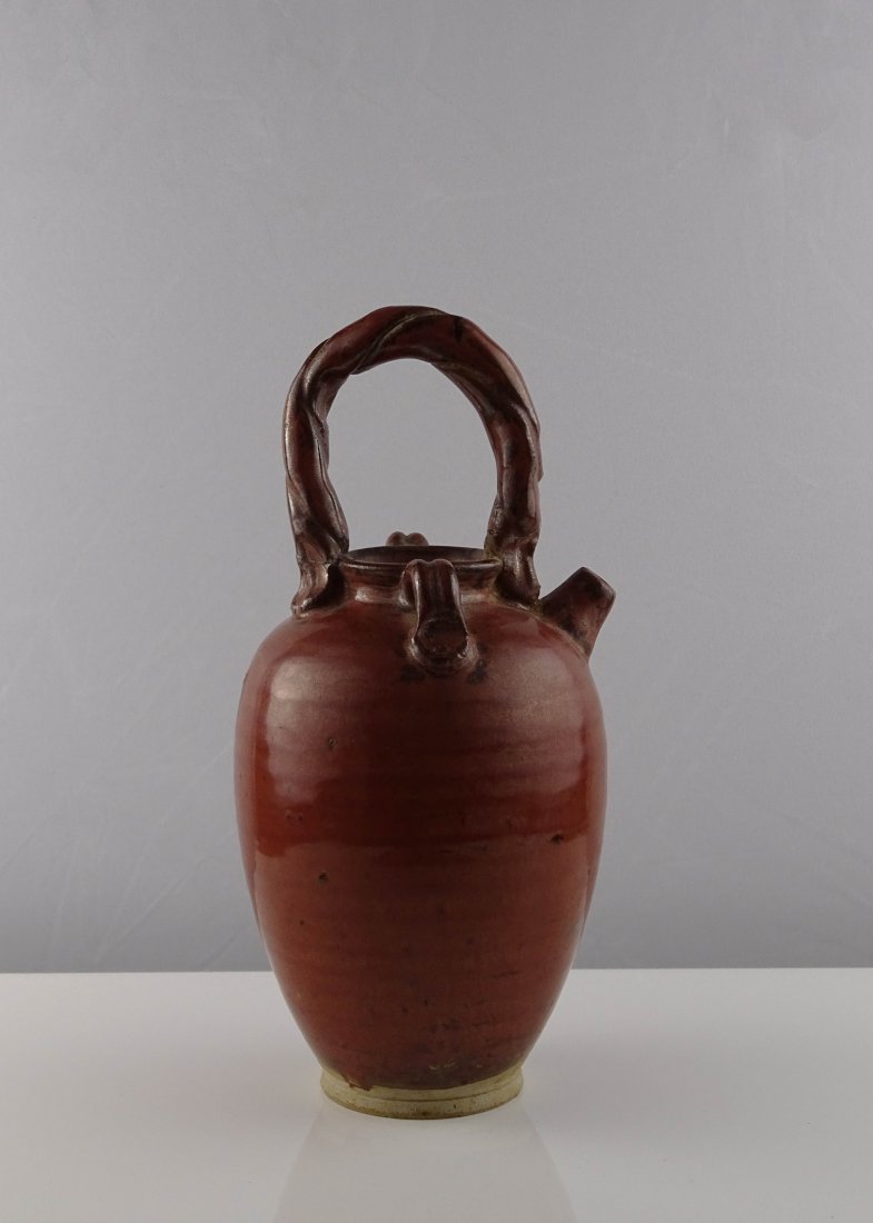 Brown Glazed Wine Pot: 酱釉提梁壶。此茶壶造型古朴特别，壶身似罐，壶嘴短小