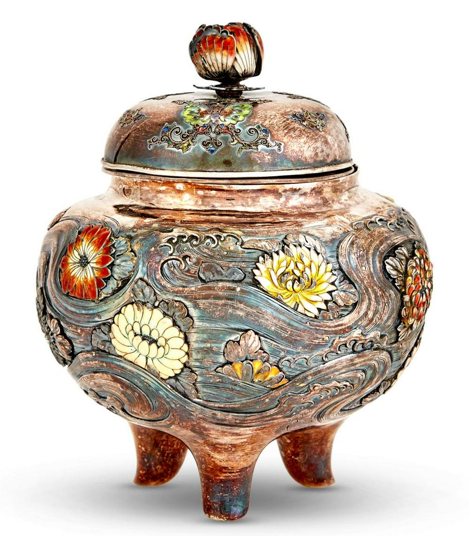 A Japanese Silver and Enamel Tripod Koro: A Japanese Silver and Enamel Tripod Koro Meiji Period Of rounded form, cast and embellished with inset enamel medallions to show blossoms on water's surface; with conforming domed cover. Height 5 1/2 
