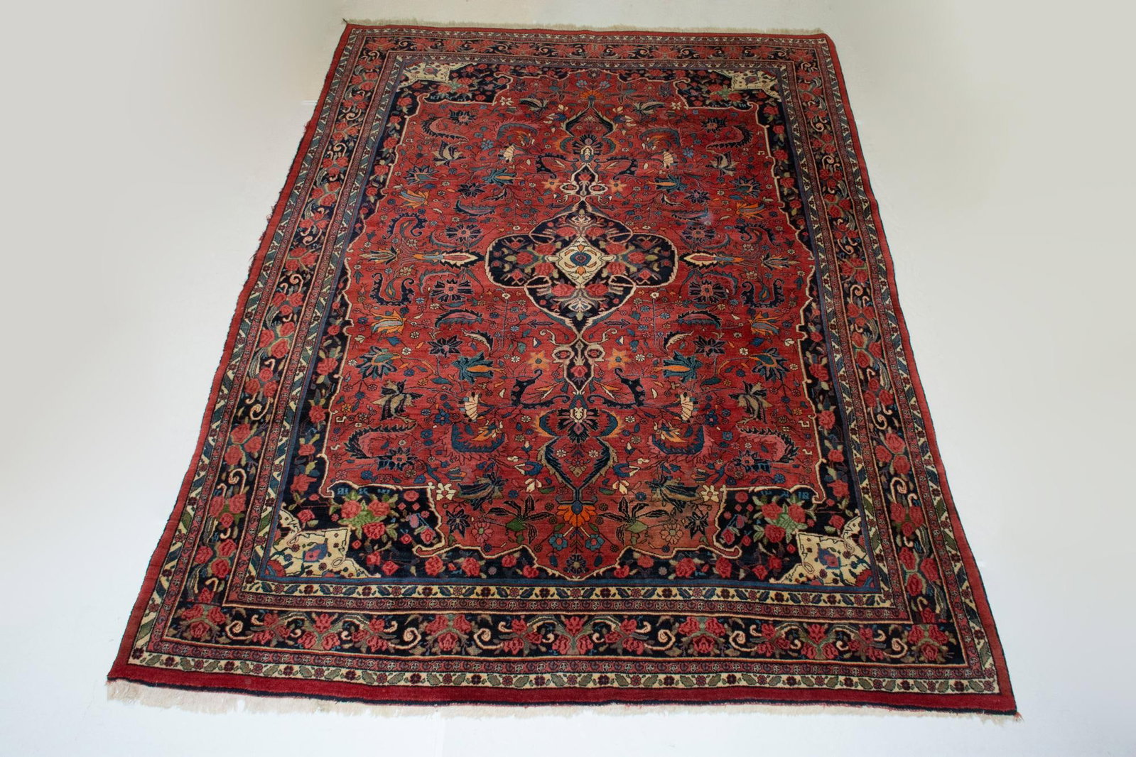 Bidjar Carpet: North Persia, circa 1935 The central pendant medallion on the madder field flanked by complementary spandrels is within a midnight blue floral vinery border. Cotton foundation. (12' 0" x 8'