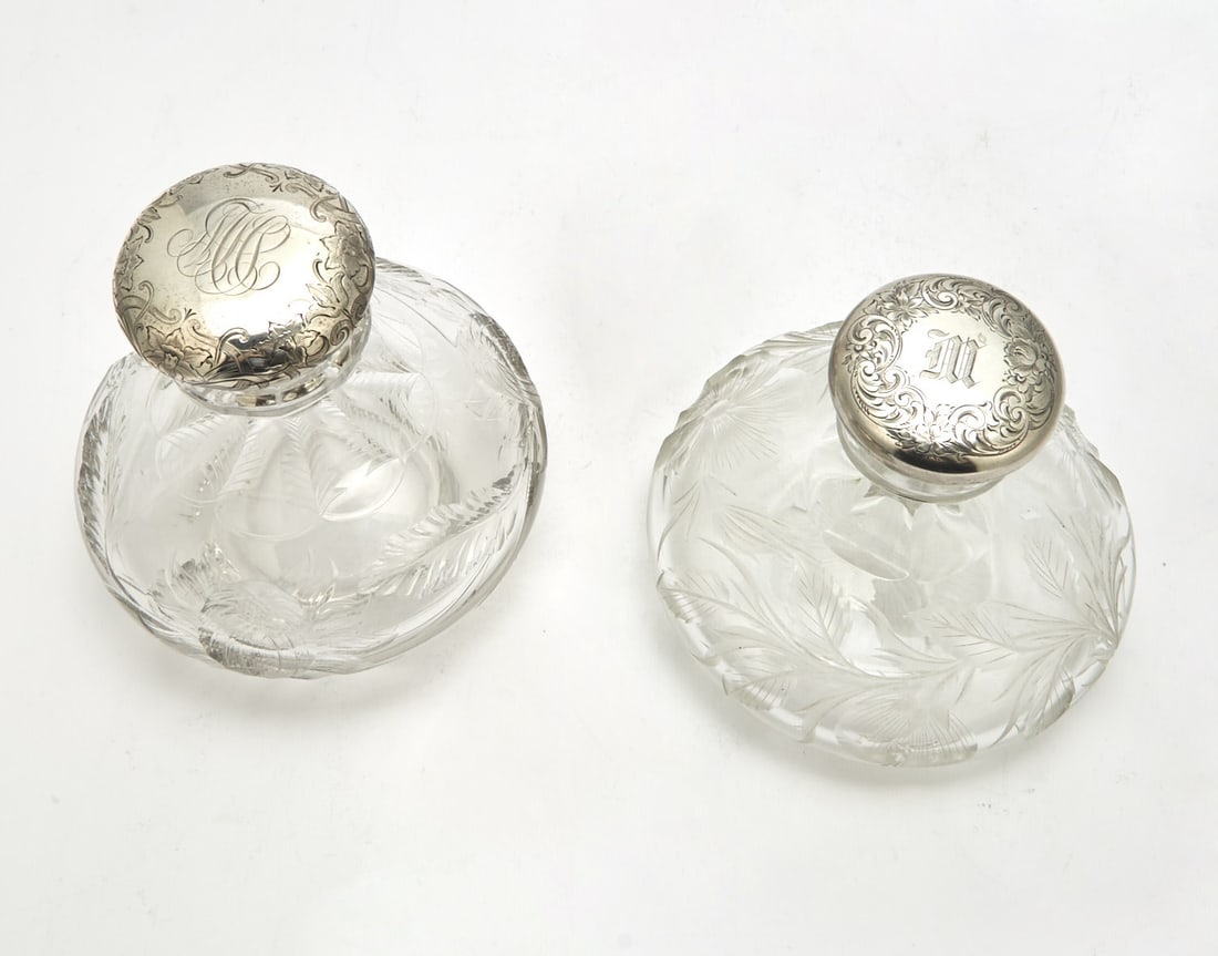 Two Gorham Sterling Silver and Cut Glass Scent Flasks: Each squat globular with floral decoration, height of larger 5 1/2 inches.