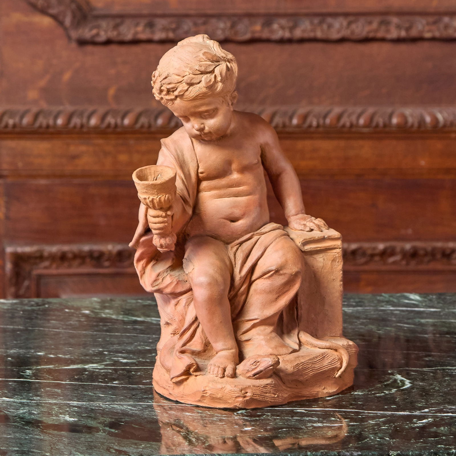 Fine Terra-Cotta Sculpture of a Boy with a Goblet 18th century: Perhaps by Louis Félix la Rue, French or FlemishHe is crowned with a laurel, his left hand resting on a book and his right raising a goblet. His feet rest on a snake or lizard.Height 11 1/.2 inch