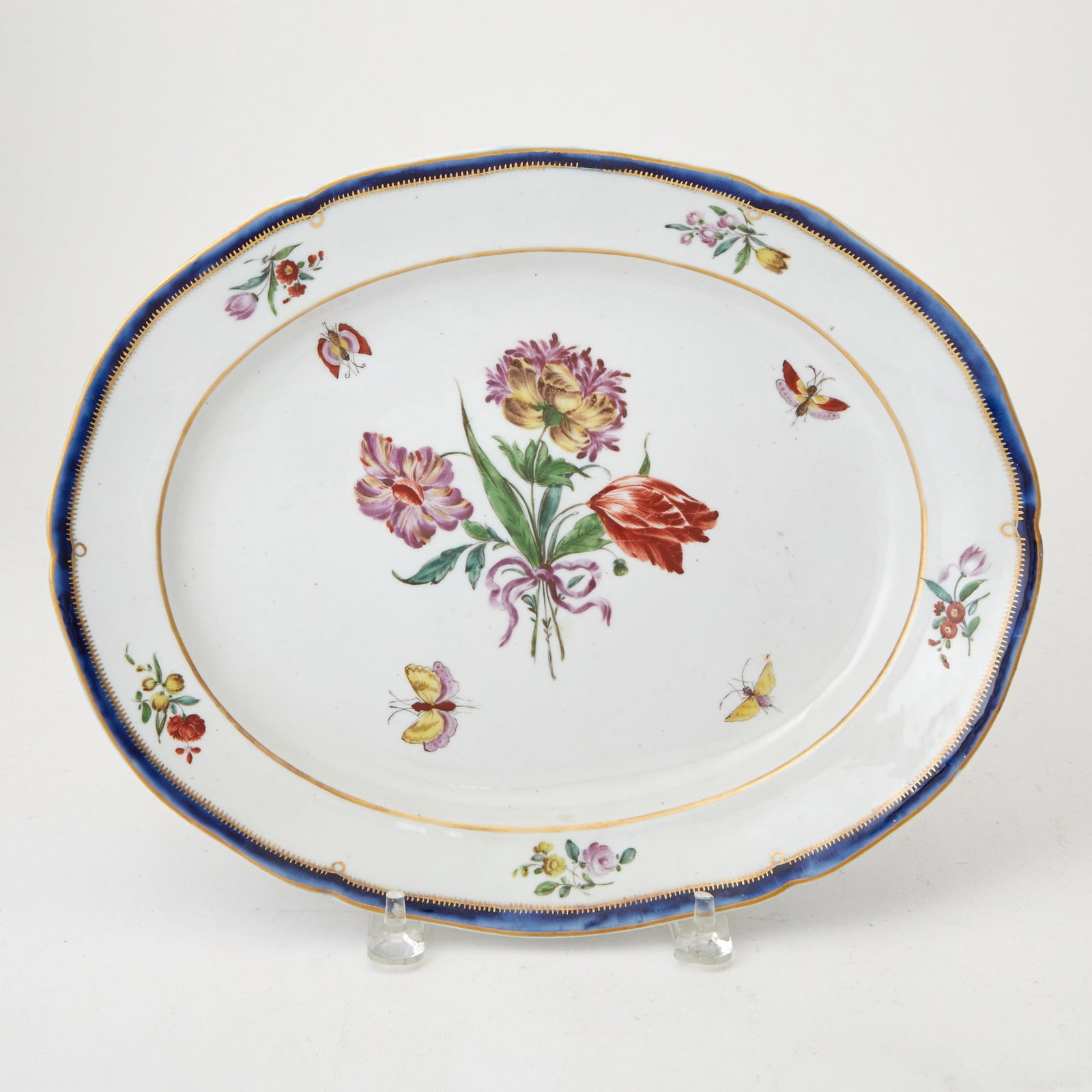 Chelsea Porcelain Oval Platter Circa 1752-1756: With red anchor mark, of oval form, centering a floral bouquet among butterflies, the border painted with floral sprays within a gilt decorated cobalt rim. Length 13 1/2 inches.