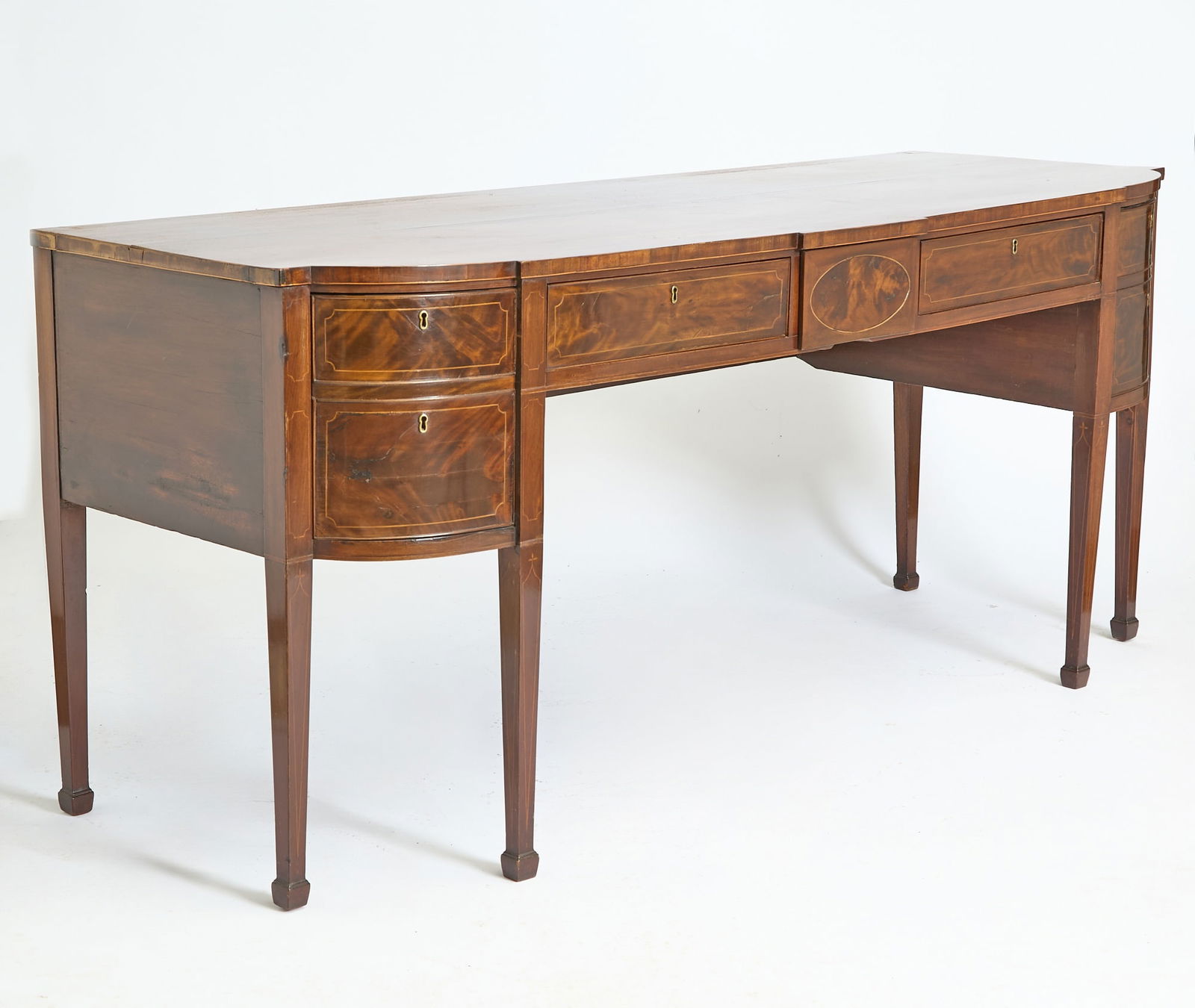 George III Inlaid Mahogany Sideboard Late 18th century: Height 37 1/4 inches, width 7 feet 2 inches, depth 30 1/2 inches. faking, cracking, scratches to top; lifting and losses to veneer; break and repair to front right leg; old marks and scratches</