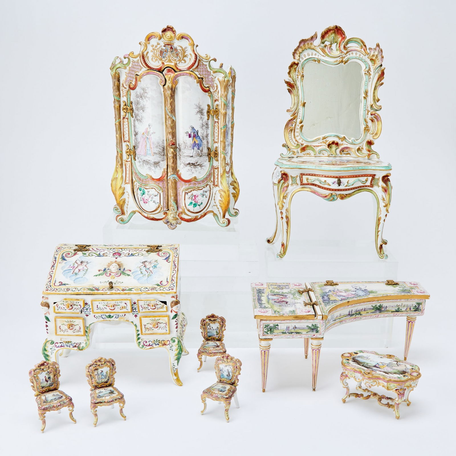Group of Nine French Faience Miniature Furniture Articles: Comprising four side chairs, dining table, piano, armoire, secretary desk, and a console with mirror, each with painted decoration. Height of console 19 inches, width 10 inches. The piano is mis