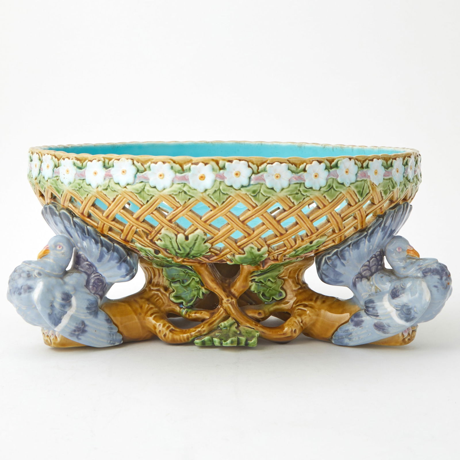 Mintons Majolica "Turkey" Basket Late 19th century: Of circular form, the upper exterior side decorated with a floral band, the interior with a turquoise colored glaze, raised on three turkey feet joined by leafy oak twigs, impressed MINTONS. Height 5