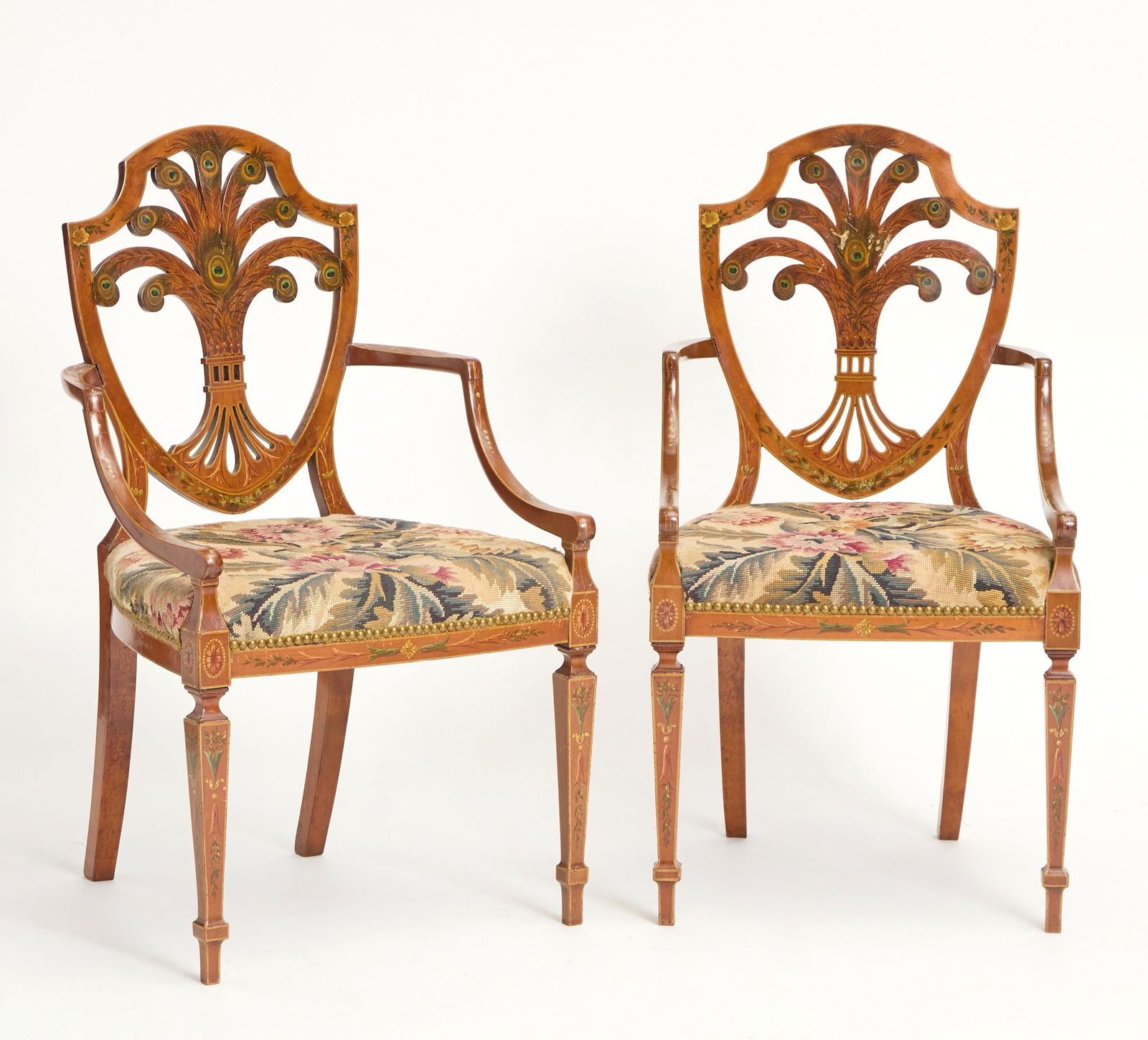 Pair of Edwardian Painted Satinwood Arm Chairs Circa 1900: Floral painted, with Peacock Feathers on the backs. Needlepoint upholstered seats. Height 37 1/2 inches , Width 21 inches, Depth 19 inches, Seat Height 18 inches Loose arms, scratches on the fin