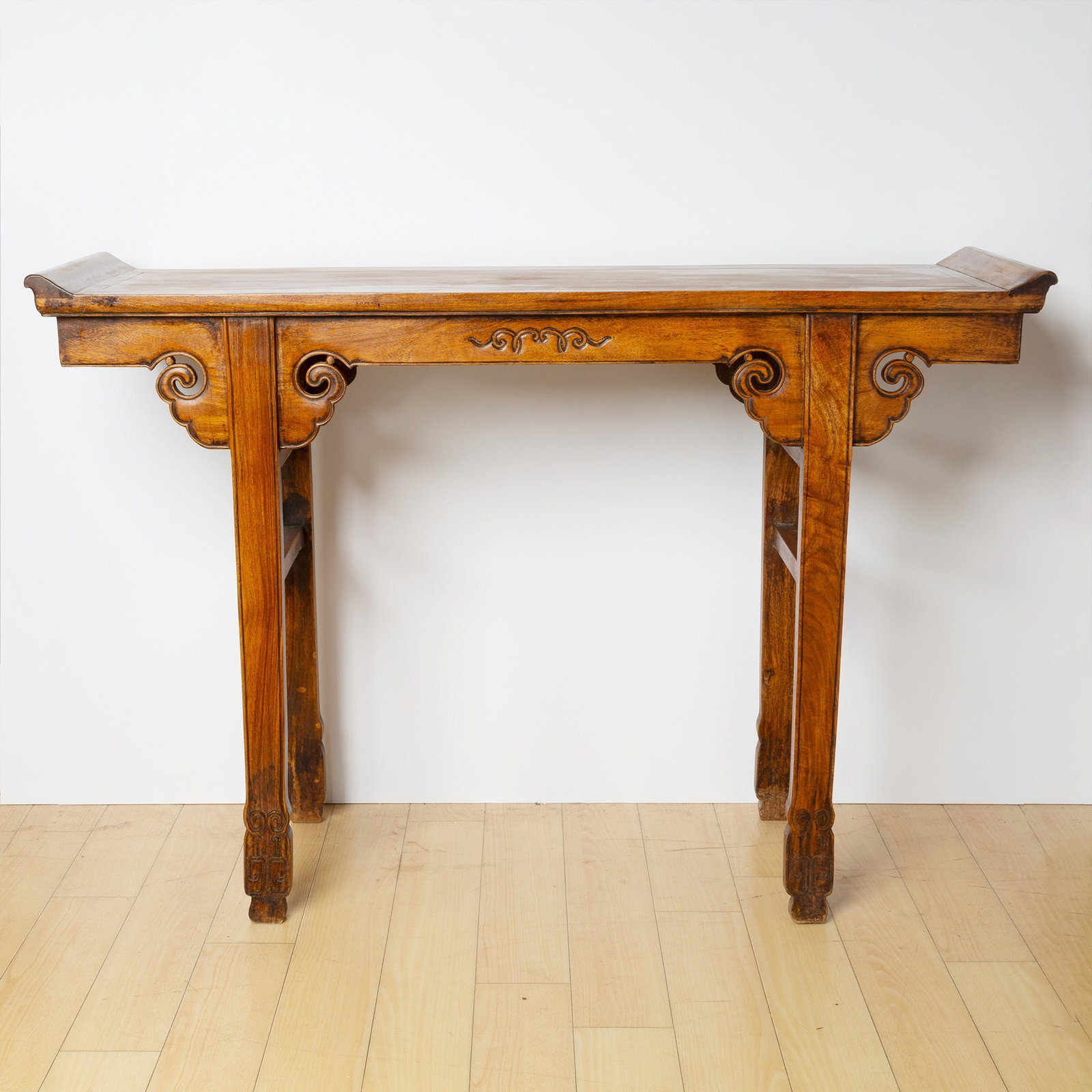 A Chinese Hualimu Altar Table: The trestle legs terminating in unusual outward-carved feet; with ruyi-form spandrels. (Height 33 inches, Width 48 inches)