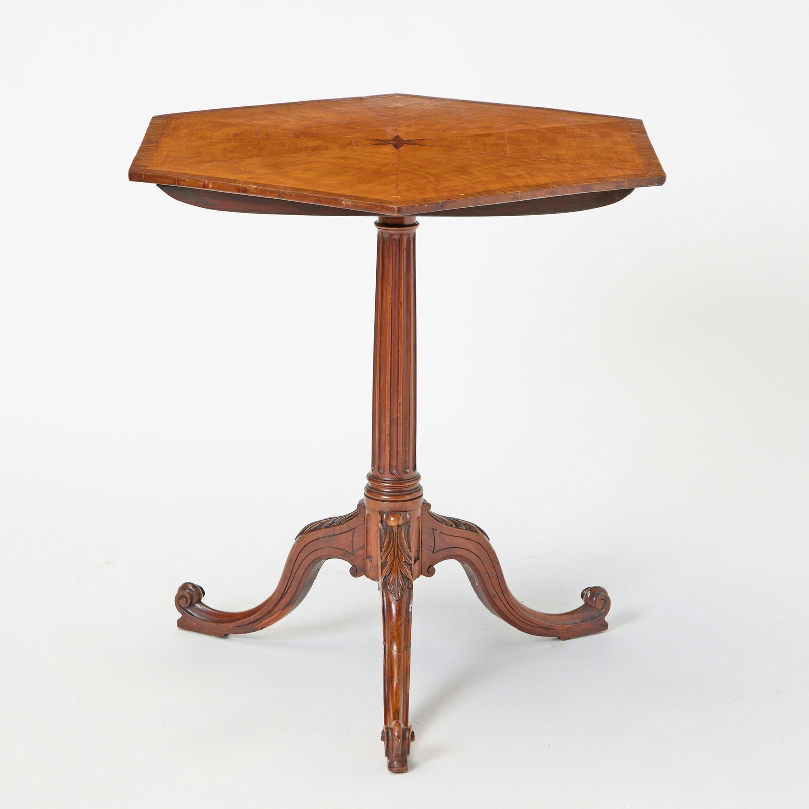 George III Tripod Table Possibly fustic, in the manner of Thomas Chippendale: The segmented banded hexagonal top tilting above a fluted stem on acanthus-carved cabriole legs ending in scroll feet. Height 27 1/2 inches (69.8 cm), diameter 28 1/2 inches (78.5 cm) <