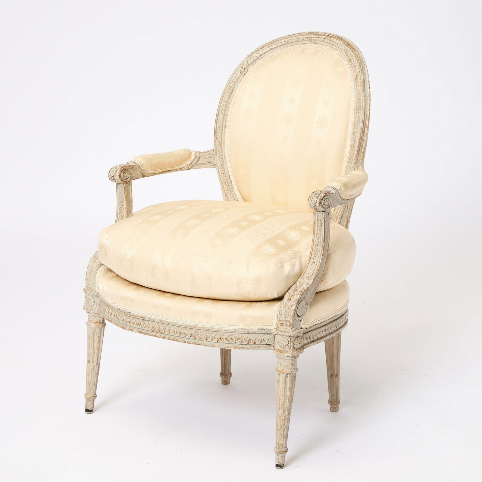 Louis XVI Painted Fauteuil: The padded oval back within a molded frame above a serpentine seat and padded arms on tapering stop-fluted legs. Height 34 5/8 inches (88 cm), width 24 inches (64 cm), depth 18 inches (45.7 cm) <