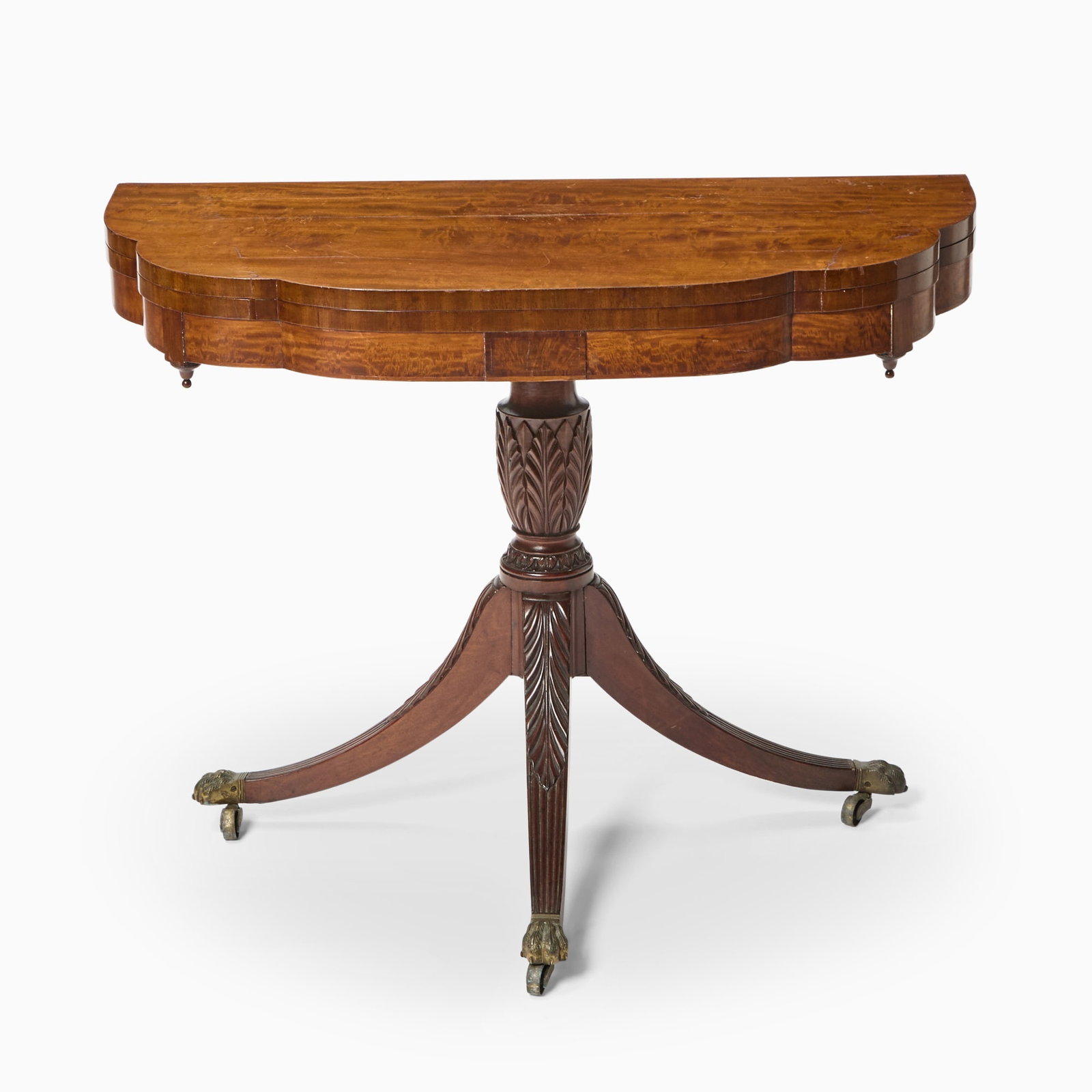 Federal Inlaid Mahogany and Satinwood “Trick-leg” Card Table Attributed to Duncan Phyfe,: The shaped top on a conforming skirt and waterleaf-carved urn-turned post issuing three carved and reeded tapering legs ending in brass hairy paw cap casters. Height 29 inches, width 36 inches, depth