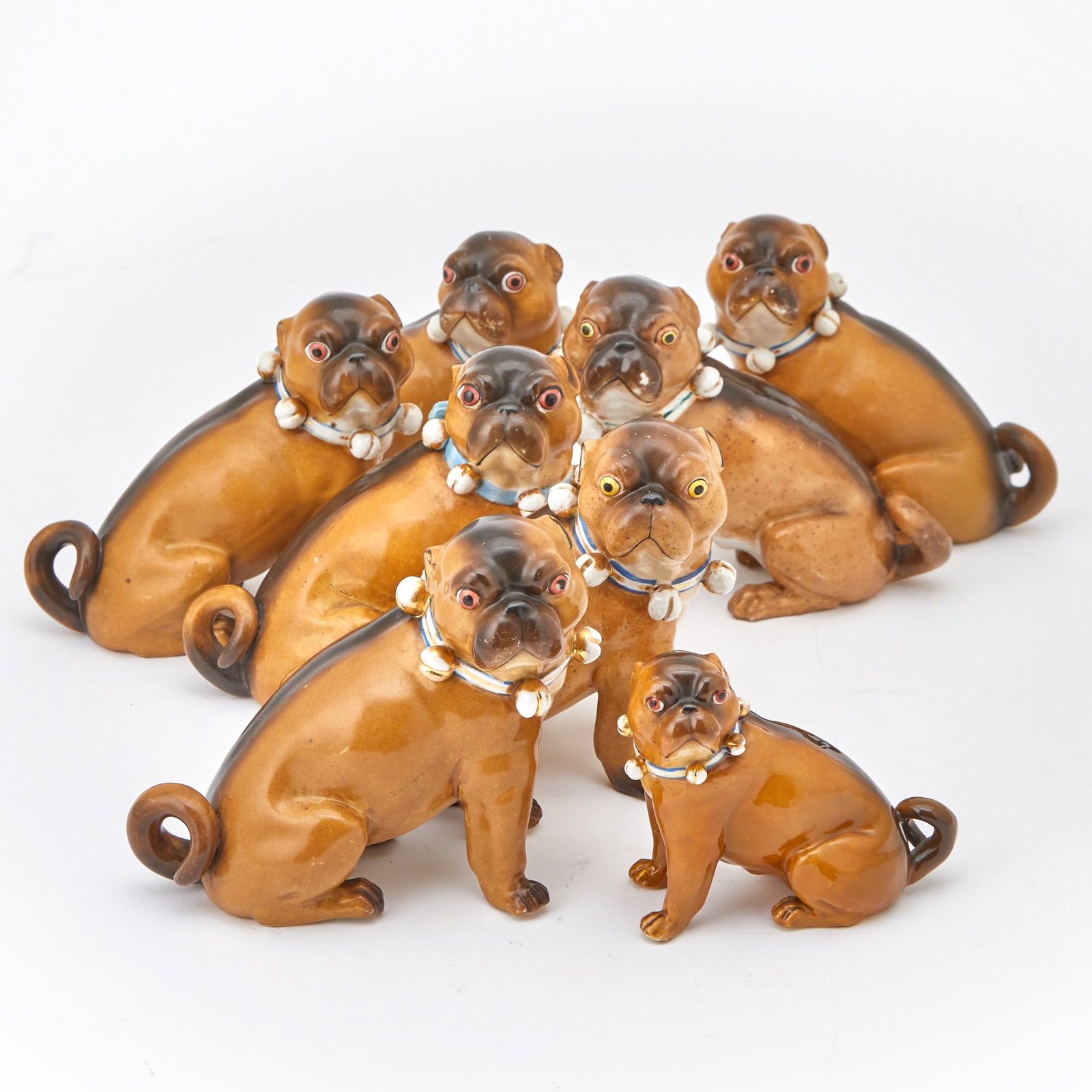 Eight Meissen Style Porcelain Models of Pugs: Estate / Collection: Property of a Fifth Avenue Philanthropist Each naturalistically modeled seated, their bell and bow collars enriched in gilt and all but one trimmed in blue, five left face and thr