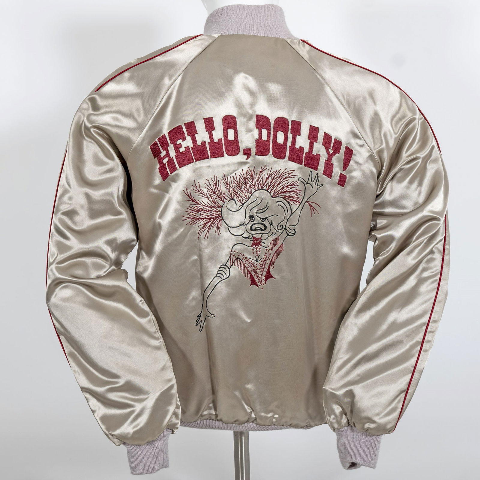 Jerry Herman's Silver Acetate Hello, Dolly! Bomber Jacket LP Designs: With Hello, Dolly! machine-embroidered logo and Al Hirschfeld-inspired Dolly on the back. Red piping on sleeves, pockets, and zippered front. The jacket embroidered 'Jerry' to left breast.