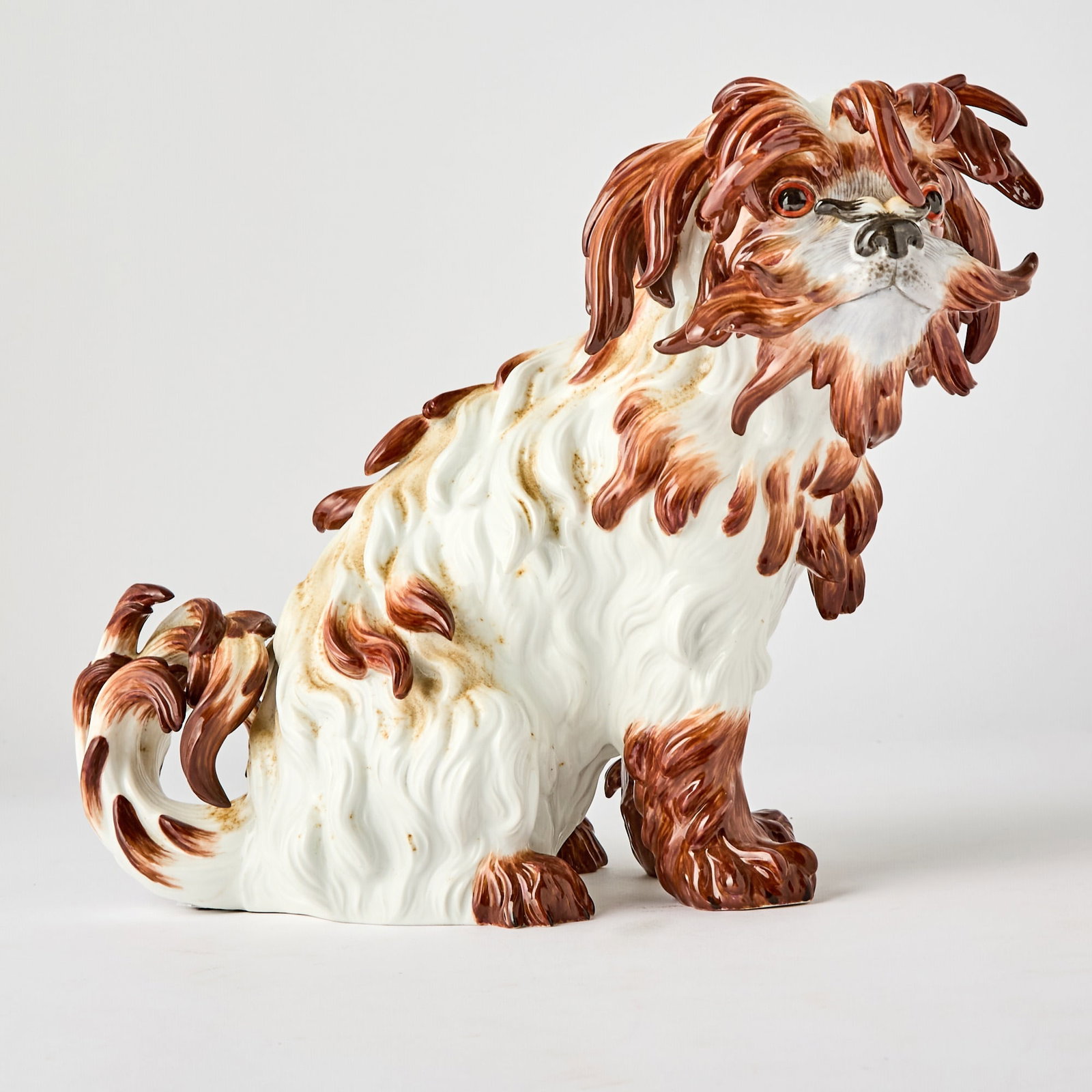 Meissen Porcelain Figure of a Bolognese Spaniel: Estate / Collection: The Collection of Joanne B. Breyer 20th Century The brown and white-painted dog seated on its haunches. Height 9 inches. (9 x 11 inches)