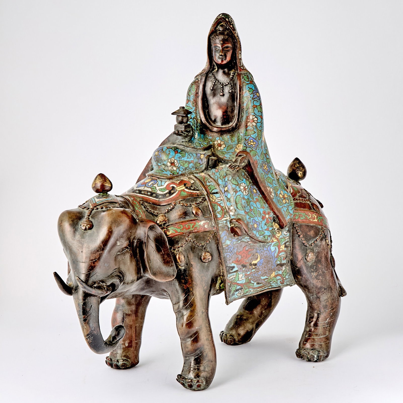 Chinese Bronze and Champlevé Enamel Figure of Guanyin Astride an Elephant: Estate / Collection: The Collection of Joanne B. Breyer The deity wearing blue, white and red and yellow floral robes, the elephant with similar trappings. Height 21 inches, length 21 inches.