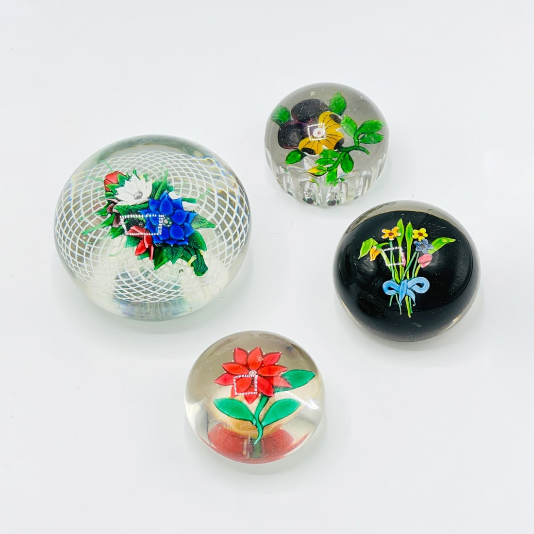 Group of Four Blown Glass Paperweights: Estate / Collection: The Collection of Joanne B. Breyer 19th and 20th Century Each with a floral design, the largest with a white lattice; the pansy example attributed to Baccarat; the tied bouquet ex