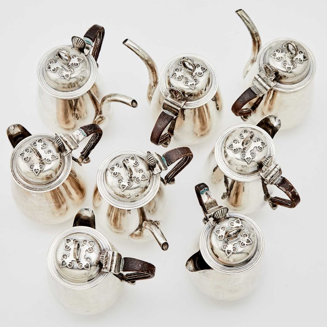 Four George VI Sterling Silver Café au Lait Sets: Richard Comyns, London, 1938 Comprising four pairs of coffee and hot milk jugs, each cover with cut card work to cover, and with leather clad handles. Heights 5 inches (13 cm), total approximately 63