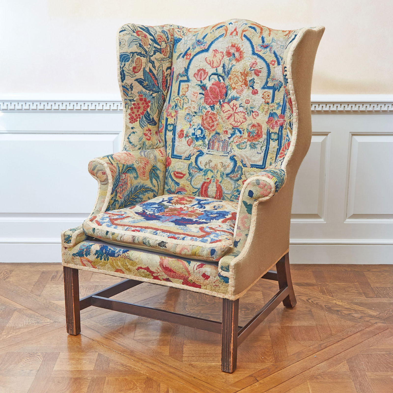 George III Style Mahogany Needlework-Upholstered Wing Armchair: The serpentine back and loose-cushioned seat with outscrolled arms, on molded square legs joined by stretchers. Height 45 inches (114.2 cm), width 31 1/2 inches (78.7 cm), depth 21 1/4 inches (54 cm)