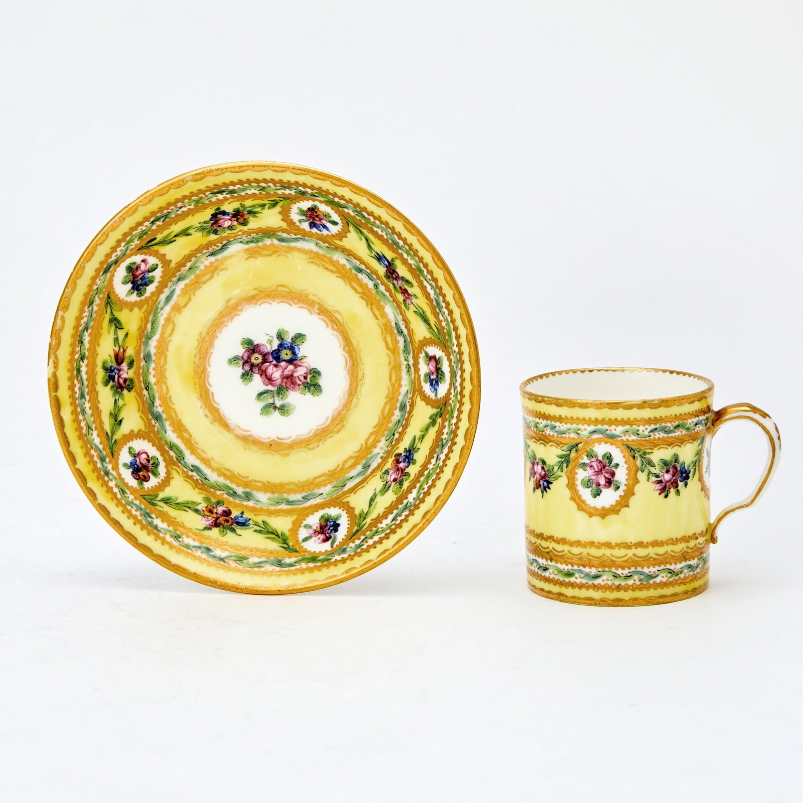 Sèvres Porcelain Yellow-Ground Teacup and Saucer: Circa 1780 Blue interlaced LS mark enclosing CC date marks, painter's mark for Antoine Capelle. Painted with gilt medallions enclosing floral sprigs of roses and cornflowers joined by further floral s