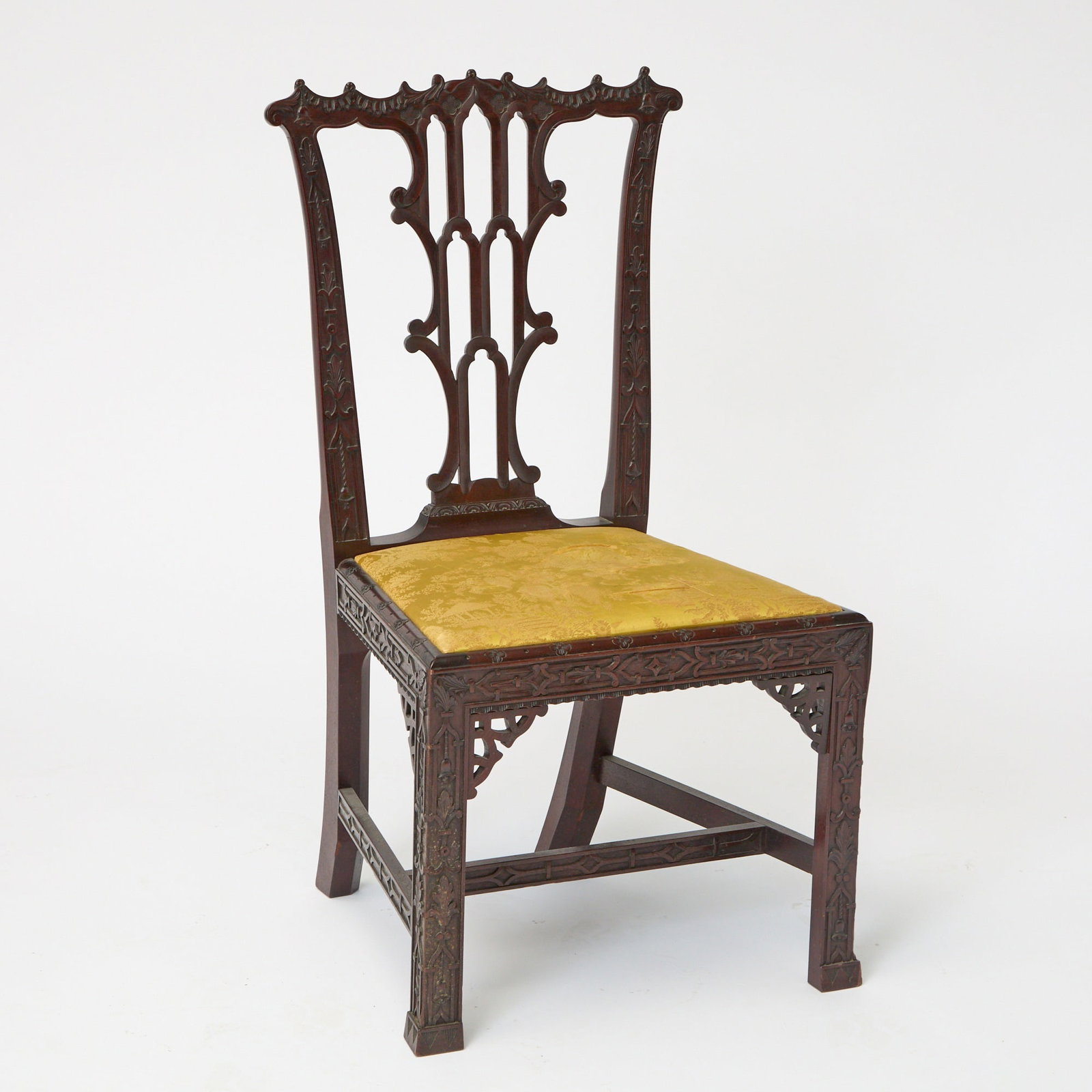 George III Style Mahogany Side Chair: The scrolling ruffle-carved toprail above a pierced tracery splat flanked by sunken fielded uprights, the seat within a frame with carved quatrefoil motif above a blind fret frieze on guttae feet; the