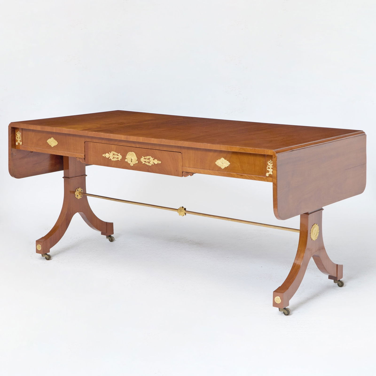 A Swedish Karl Johan Gilt-Bronze Mounted Mahogany Drop-Leaf Writing-Table: Probably by Lorentz Wilhelm Lundelius, circa 1815-20 The rectangular top with twin-flap above a plain frieze centered by a drawer applied with a gilt-bronze escutcheon in the shape of entwined cornuco