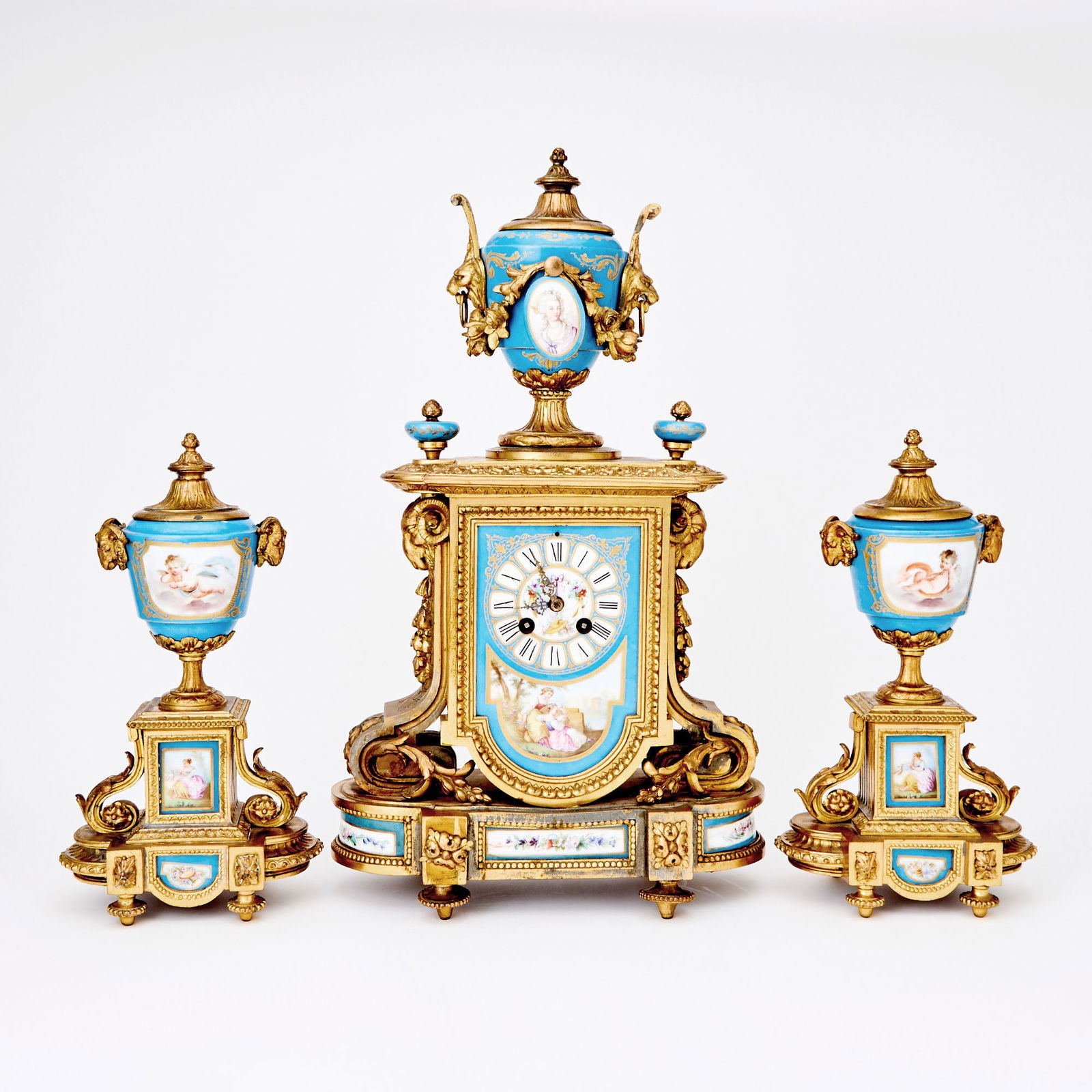 Louis XVI Style Gilt-Metal and Turquoise-Ground Porcelain Three-Piece Clock Garniture: Late 19th/early 20th century In the S?vres style, comprising a mantel clock and a pair of footed urns with reversible covers, including candle nozzles on one side. Height of clock 19 1/2 inches, width