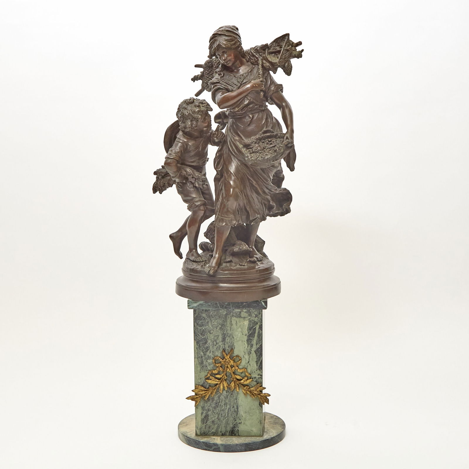 Bronze Figural Group of a Mother and Child: After a model by Auguste Moreau, 20th century Depicting a woman gathering firewood and a putto. Height 24 1/4 inches; Together with a Pedestal Qty: (2)
