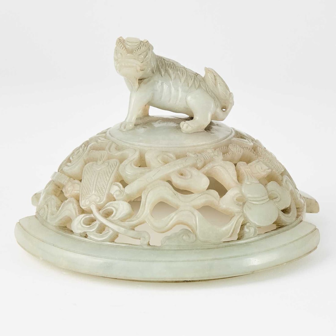 A Chinese Carved White Jade Cover 18th Century: The domed, openwork cover carved to show 'bajixiang' emblems encircling a qilin finial. (Diameter 5 1/2 inches)
