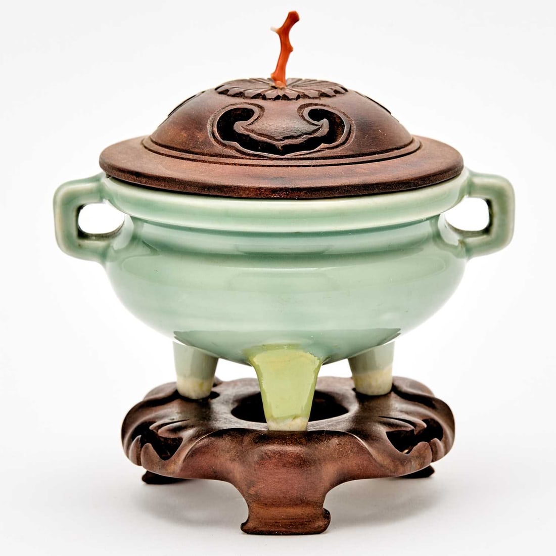 A Chinese Celadon Glazed Tripod Censer and Stand Qing Dynasty: Of compressed form with twin looped handles; the wood cover with a coral finial. (Width 4 3/4 inches)