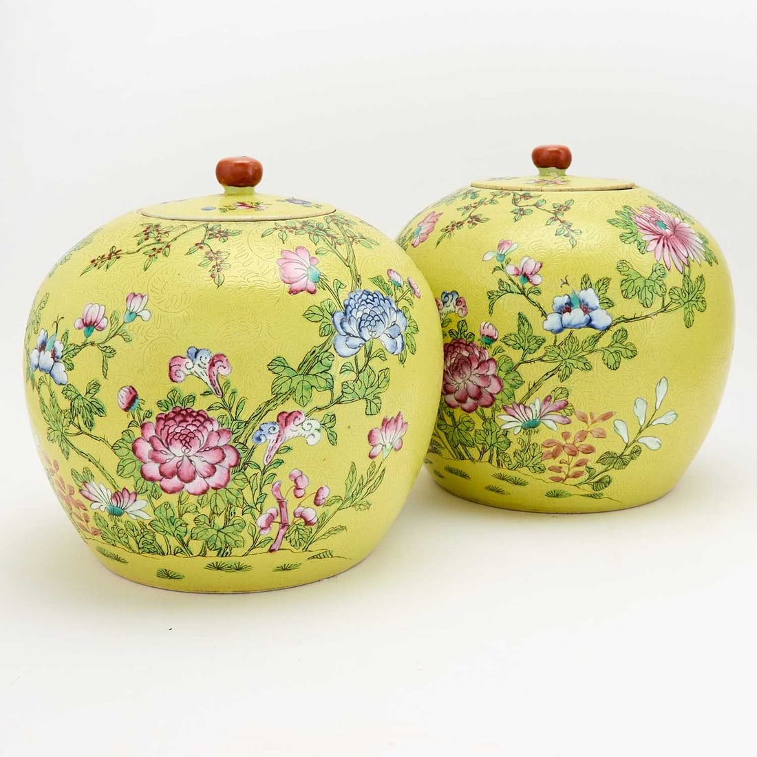A Pair of Chinese Yellow Ground Porcelain Jars and Covers Republic Period: Of globular form; enameled with varying blossoms and sprays on leafy branches, and incised to show tendrils spreading the ground. (Height 9 inches)